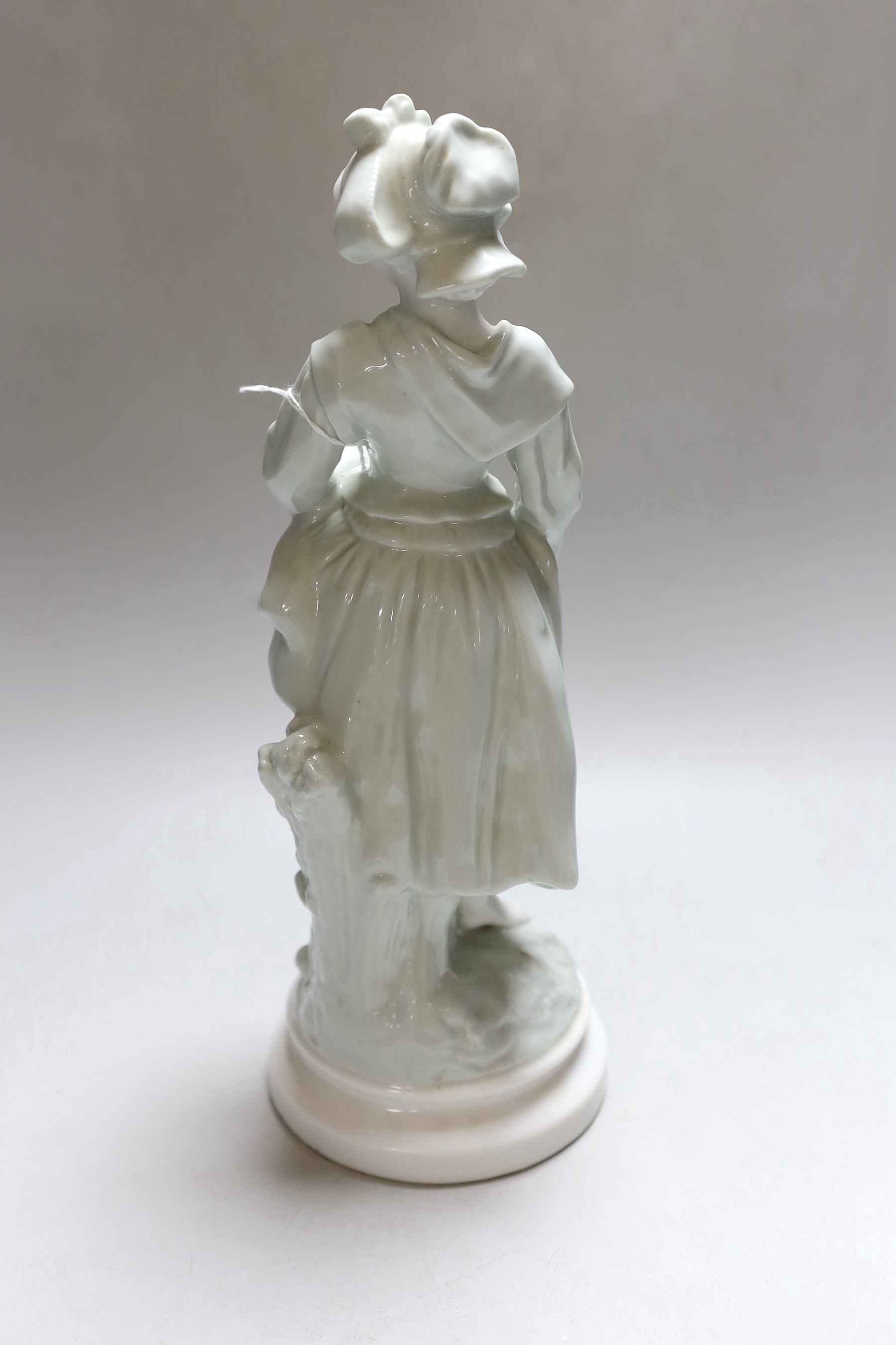 A celadon glazed figure of a girl, barefooted beside a tree, holding her skirt off the ground, c.1885-90, 32cm high